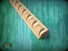 Load image into Gallery viewer, A wooden molding with a curved design is shown against a green textured background.

