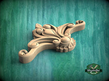 Load image into Gallery viewer, A wooden carving with intricate scrollwork and floral designs is displayed against a green background.

