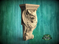 A carved stone wall bracket with a fierce-looking lion's head design, set against a green background.