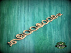 a decorative wooden piece with a curved design, placed against a green background.