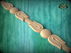A wooden decorative element with a curved design, resembling a flower or leaf shape, is displayed against a green textured background.