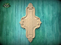 a decorative wooden panel with an intricate design, mounted on a green wooden surface.