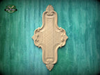 a decorative wooden panel with an intricate design, mounted on a green wooden surface.