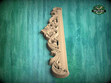 Load image into Gallery viewer, A decorative wooden carving or panel with intricate floral and scrollwork designs is displayed against a green textured background.
