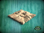 A decorative wooden panel with an intricate floral design, placed on a green textured background.