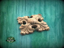 Load image into Gallery viewer, A wooden ornamental piece with a floral design sits on a green wooden surface.
