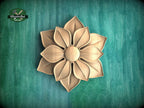 A wooden flower carving is displayed against a green background.