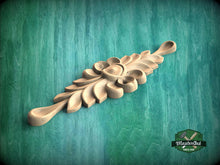 Load image into Gallery viewer, A wooden carving with a floral design is displayed against a green background.
