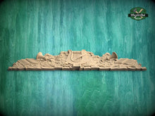 Load image into Gallery viewer, A wooden carving of a harp and other musical instruments is displayed against a green background.
