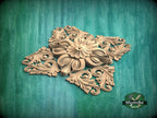 A decorative wooden carving with intricate floral and leaf-like patterns is displayed against a green background.