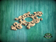 Load image into Gallery viewer, A decorative wooden carving with intricate scrollwork and floral elements is displayed against a green textured background.
