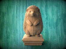 Load image into Gallery viewer, A wooden hedgehog statue is displayed on a wooden pedestal against a green background.
