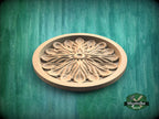 A wooden ornamental piece with a floral design, placed on a green textured background.