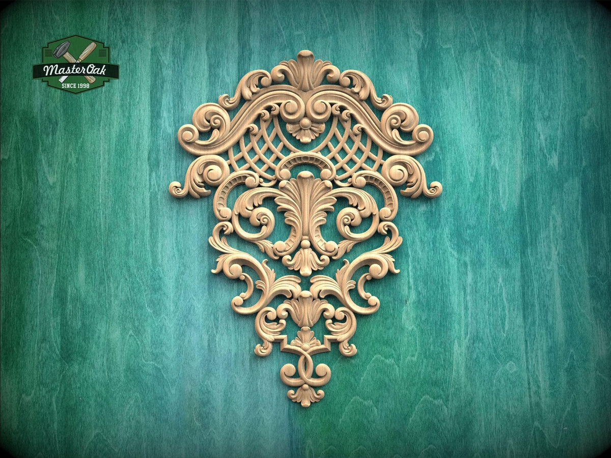 an ornate, carved wooden piece with intricate scrollwork and floral designs, mounted on a green wooden surface.