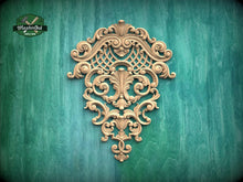 Load image into Gallery viewer, an ornate, carved wooden piece with intricate scrollwork and floral designs, mounted on a green wooden surface.
