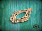 A decorative wooden frame with intricate scrollwork and floral patterns is displayed against a green wooden background.