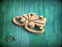 Load image into Gallery viewer, A wooden carving of a stylized flower or floral design is displayed against a teal-colored background.
