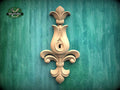 a wooden ornamental piece with a floral design, mounted on a green textured wall.