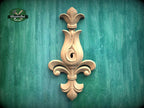 a wooden ornamental piece with a floral design, mounted on a green textured wall.