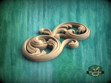 Load image into Gallery viewer, A wooden carving of a stylized floral design is displayed against a teal background.
