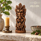 a wooden sculpture of a face with leaves, a candle, and a bowl of acorns on a stone surface.