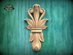 a decorative wooden carving of a stylized flower or plant on a green background.
