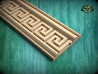 a wooden carving with a geometric pattern, placed on a green wooden surface.