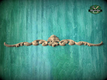 Load image into Gallery viewer, A decorative wooden carving with an ornate design is displayed against a textured green background.
