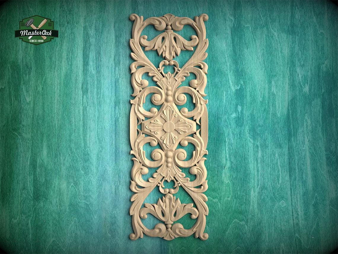 an ornate, carved wooden panel with intricate floral and scroll designs, mounted on a green wooden surface.