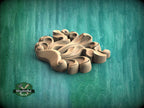 A wooden carving with intricate, organic shapes sits on a green background.