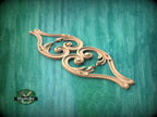 A decorative wooden carving with intricate scrollwork is displayed against a green textured background.