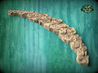 A wooden carving of a rose-shaped object with intricate details, displayed against a teal background.