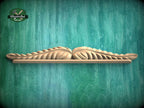 A wooden shelf with a decorative leaf-like design on it, set against a green textured background.