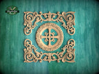 an ornate, carved wooden design with intricate scrollwork and a central motif, set against a teal background.