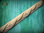 a decorative wooden border with intricate floral designs, set against a green wooden background.
