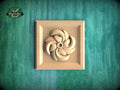 A wooden relief in the shape of a flower is displayed against a green textured background.