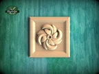 A wooden relief in the shape of a flower is displayed against a green textured background.