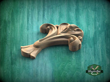 Load image into Gallery viewer, A wooden carving of a stylized flower or plant is displayed against a green background.
