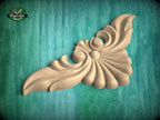 A decorative wooden carving in the shape of a leaf or flower is displayed against a teal background.