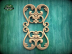 a decorative wooden carving with intricate scrollwork and floral designs, set against a green background.