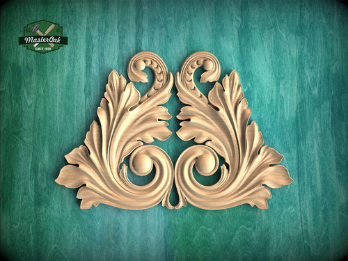 a decorative wooden carving of two ornate leaves or flowers, with intricate scrollwork and a symmetrical design, set against a green background.