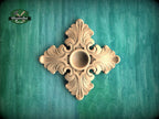 a decorative wooden piece with an intricate design, placed against a green background.