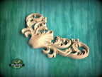 A decorative wooden carving with intricate scrollwork is displayed against a green background.