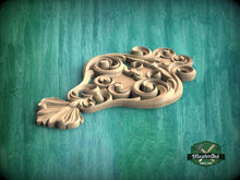 Load image into Gallery viewer, A wooden carving with intricate scrollwork is displayed against a green background.
