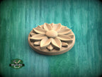 A wooden flower-shaped object is displayed against a green background.