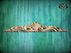 A decorative wooden carving with a shell-like design is displayed against a teal-colored background.