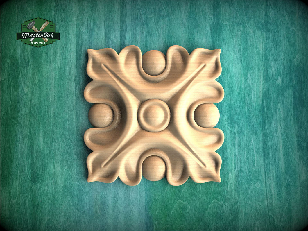a square, ornate, wooden carving with a floral design on a green background.