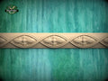 a decorative border made of wood, with intricate floral designs carved into it, set against a textured green background.