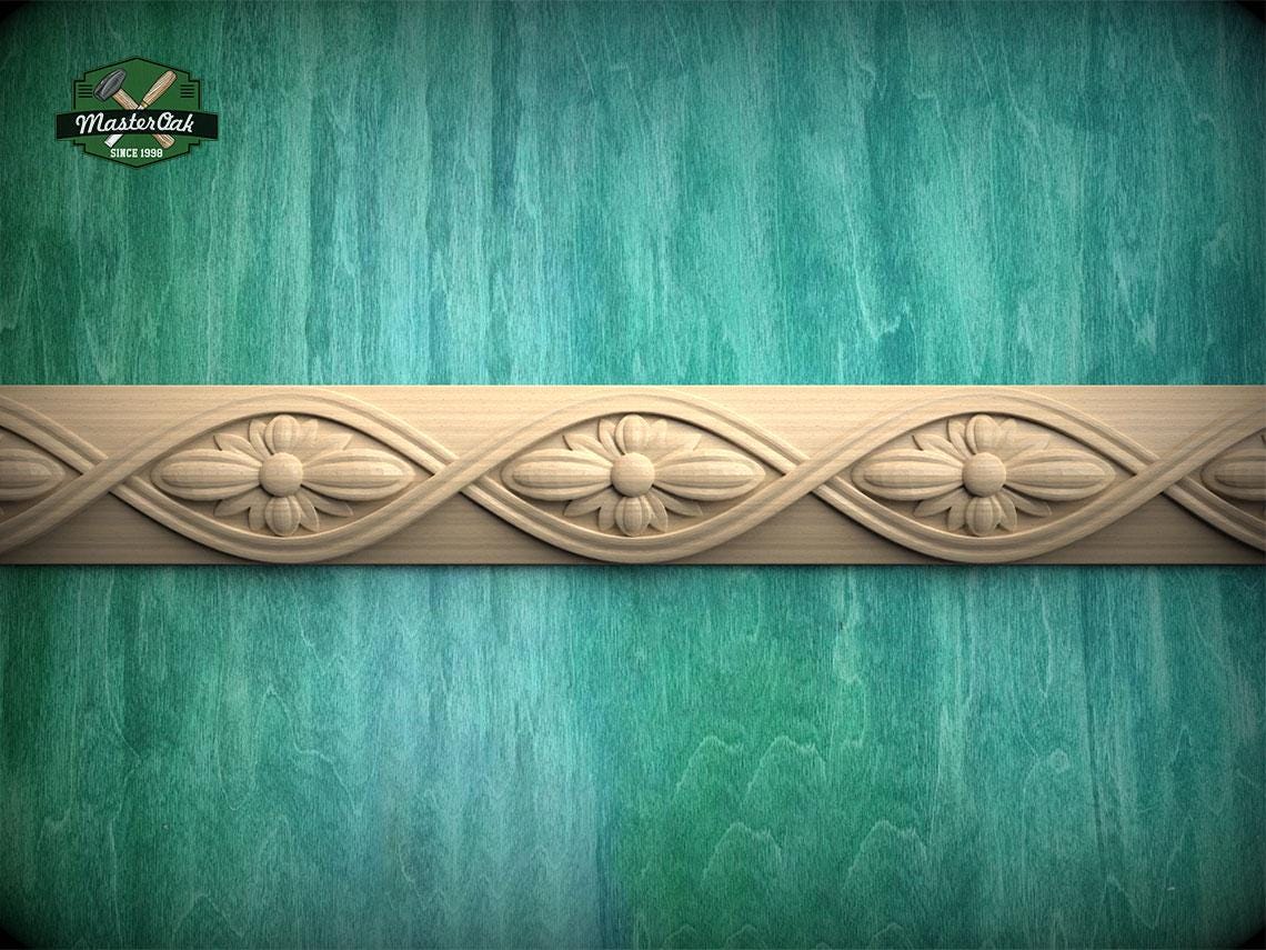 a decorative border made of wood, with intricate floral designs carved into it, set against a textured green background.