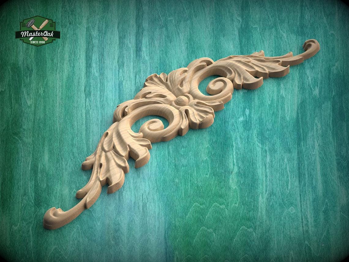 A decorative wooden carving with intricate scrollwork is displayed against a green wooden background.